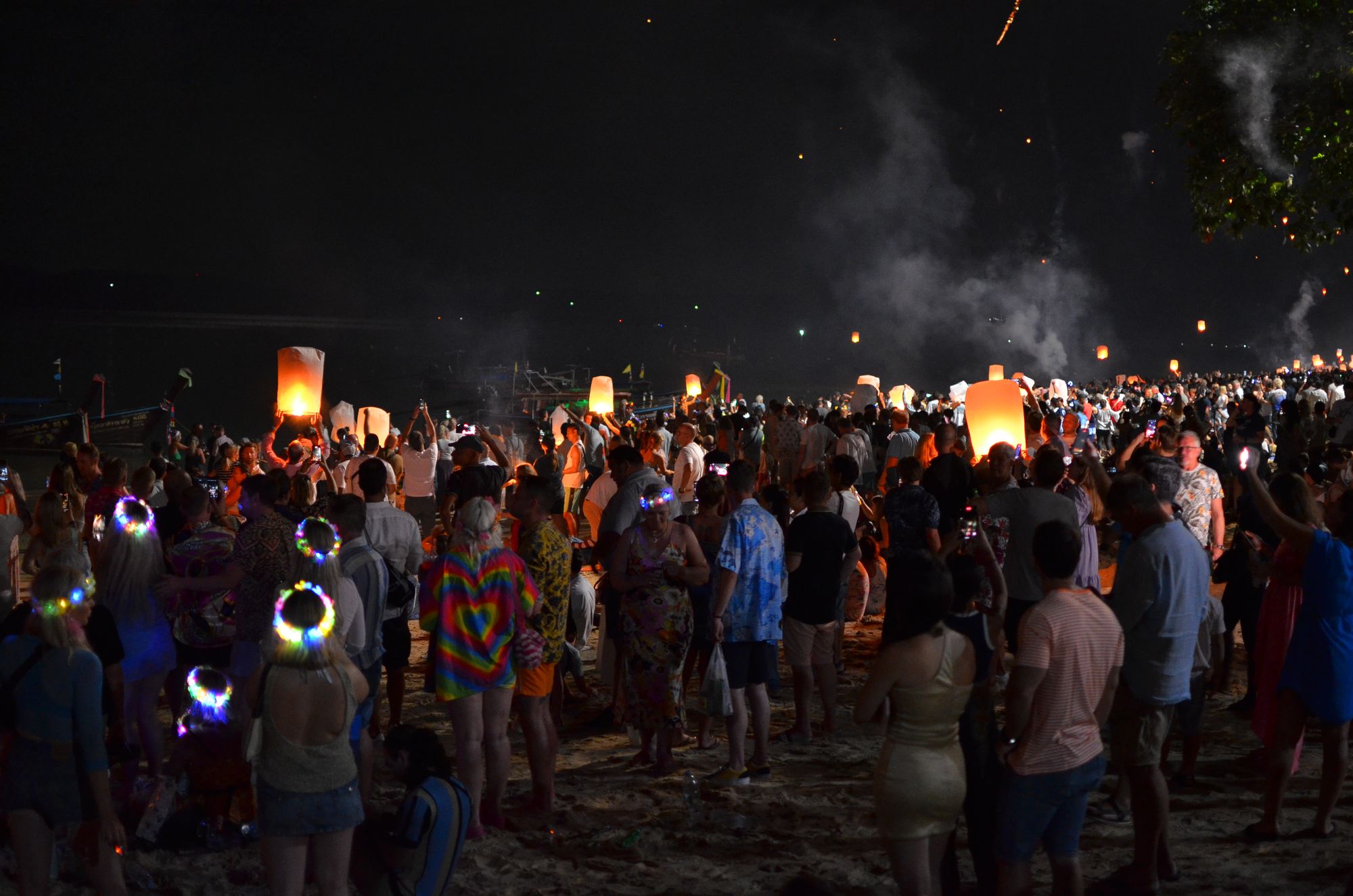 People on the beach lighting and releasing paper lanterns