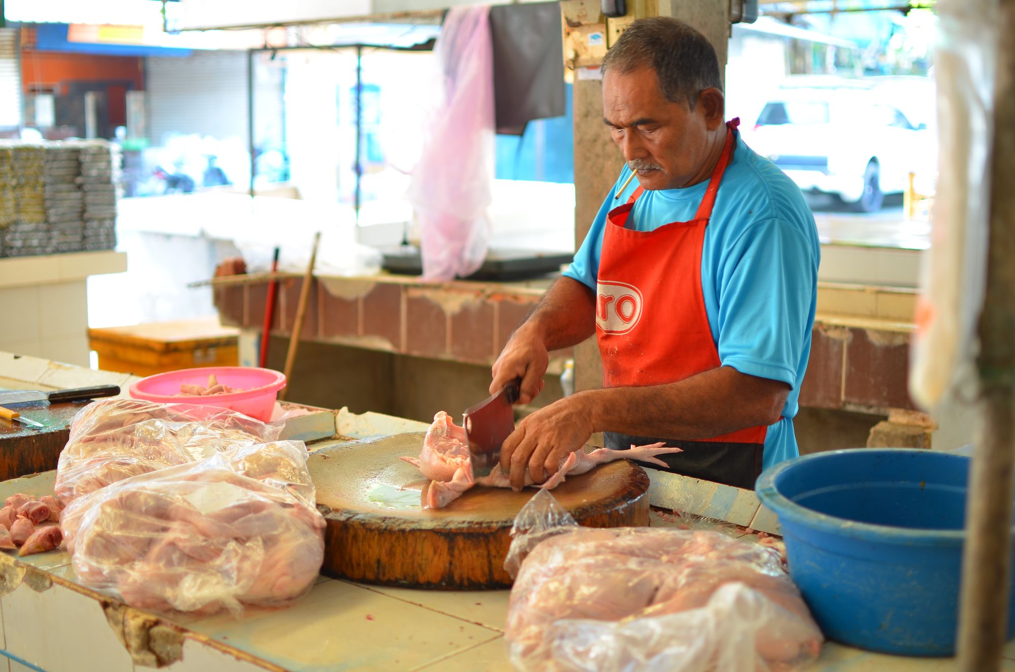 Preparing chicken at the market (note the cigarette)